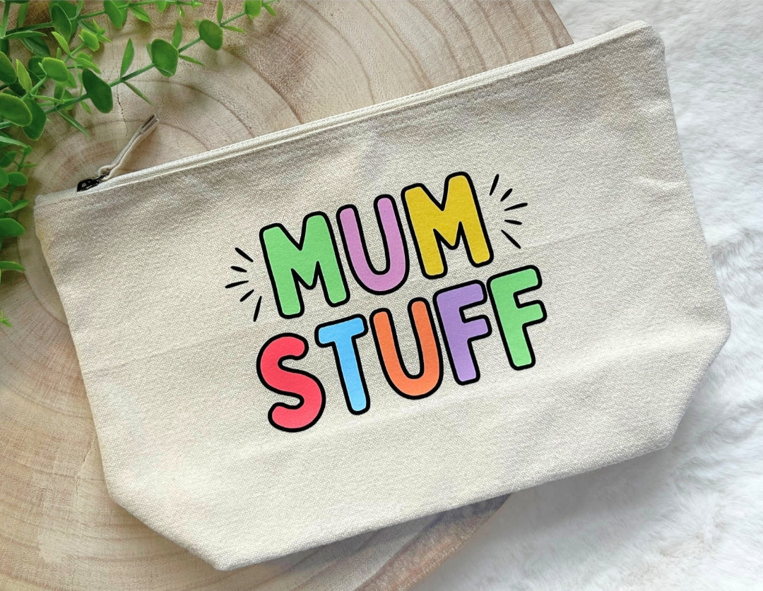 Beige pouch with 'MUM STUFF' text in colorful letters on a wooden surface.