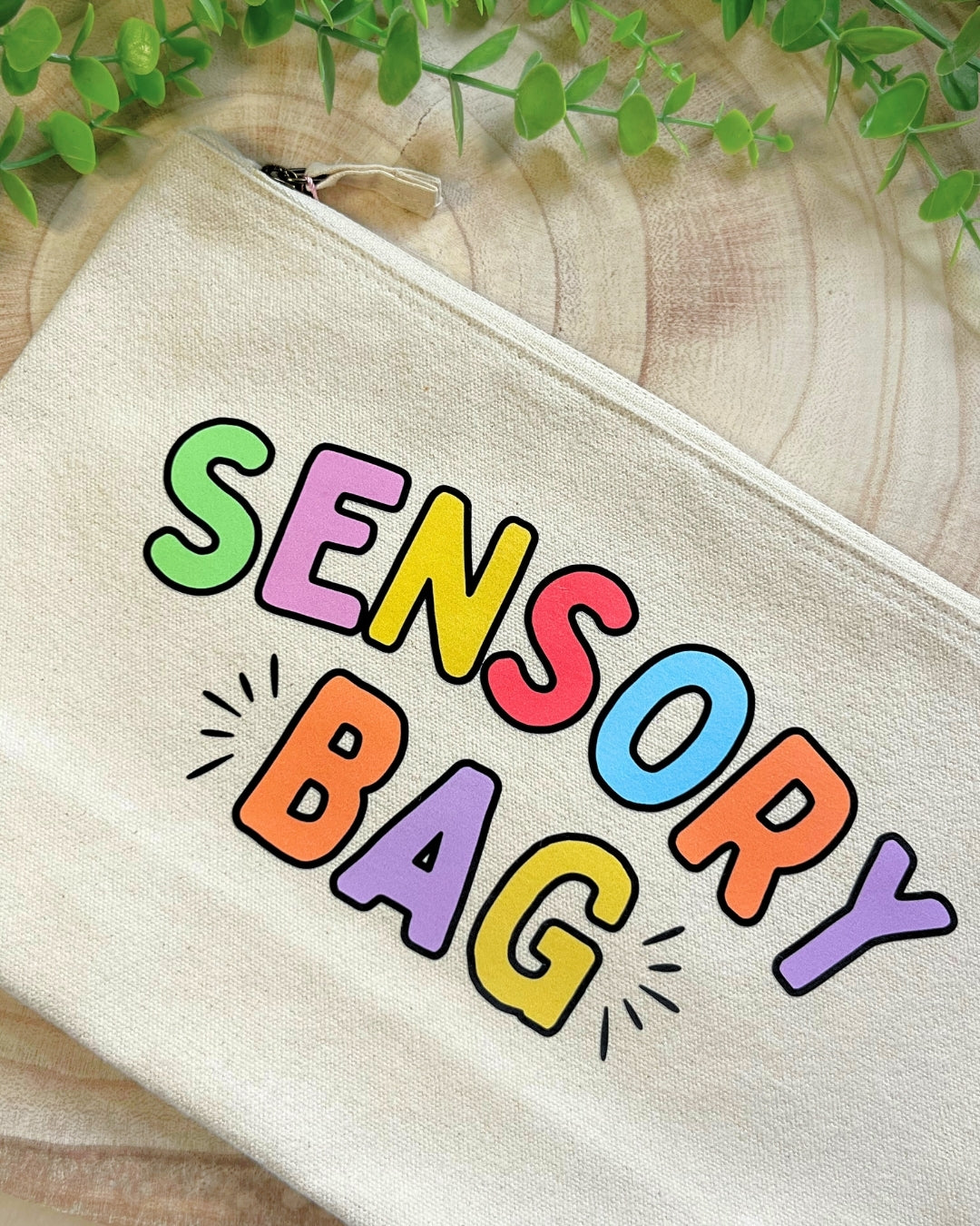 Beige canvas sensory bag with colourful lettering, perfect for makeup, pens, and everyday storage.