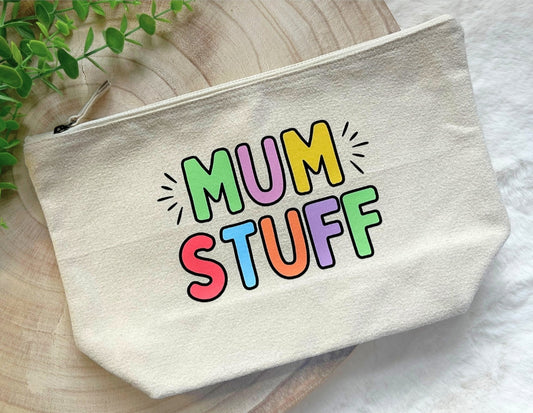 Beige pouch with 'MUM STUFF' text in colorful letters on a wooden surface.