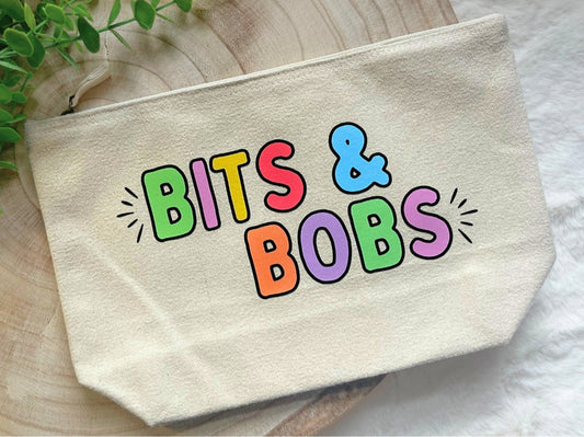 Canvas zip pouch with rainbow text “Bits & Bobs,” durable storage for makeup, stationery, or accessories.
