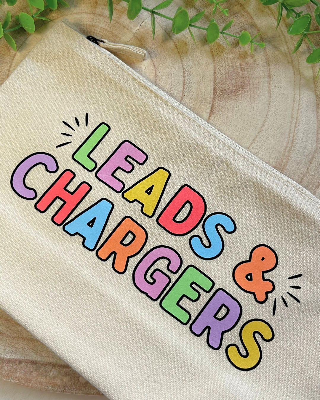 Cream coloured pouch with bold rainbow lettering “Leads & Chargers" with a metal zipper