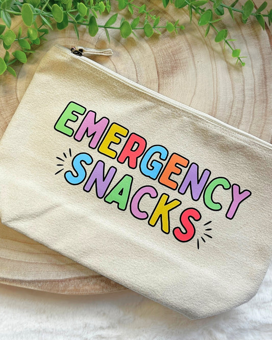 Cream coloured zip pouch with bold rainbow lettering “Emergency Snacks"